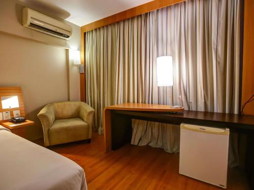 a hotel room with a desk and a chair at Novotel RJ Santos Dumont in Rio de Janeiro