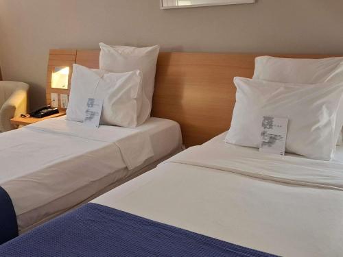 two beds in a hotel room with price tags on them at Novotel RJ Santos Dumont in Rio de Janeiro