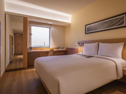 a hotel room with a large bed and a desk at ibis Jaipur City Centre - An Accor Brand in Jaipur