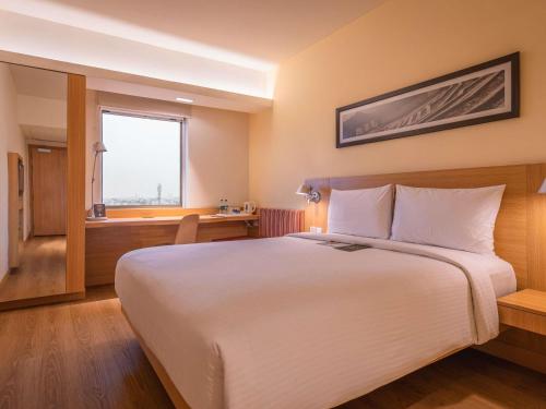 a hotel room with a large bed and a desk at ibis Jaipur City Centre - An Accor Brand in Jaipur