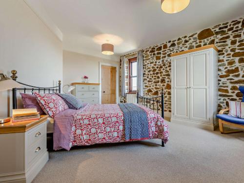 a bedroom with a bed and a stone wall at 4 Bed in Bude SSHAM in Stratton