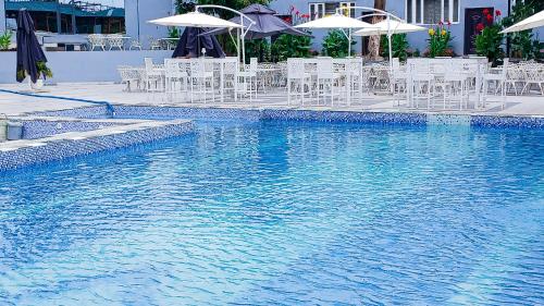a pool with white chairs and tables and umbrellas at AA Hotels, Suites and Apartments in Abuja