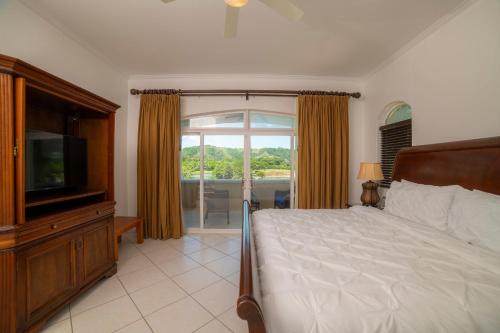 a bedroom with a bed and a tv and a window at Colina 5D 3 bdr Garden View in Los Suenos in Herradura