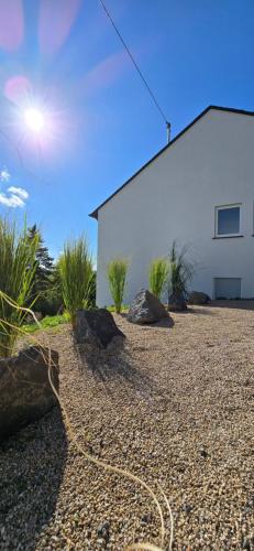 a yard with rocks and a white building at RINGZEIT-Lodge in Herresbach