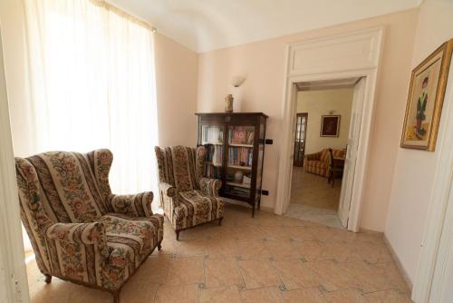 a living room with two chairs and a book shelf at Residence Acropoli in Siracusa