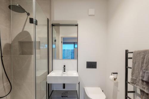 Un baño blanco con lavabo y ducha. en The Hideout - Serenity by design, en Exmouth