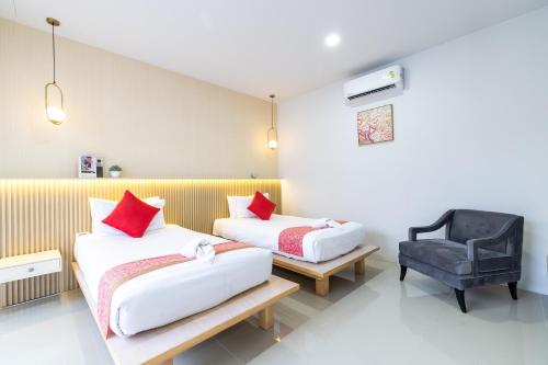 a hotel room with two beds and a chair at Andaman Sea Best Pool Access and Villas in Phuket Town