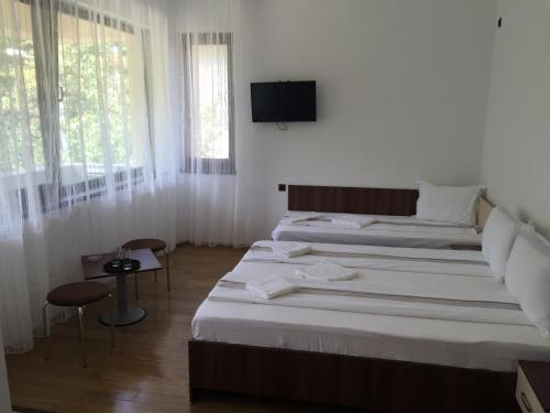 two beds in a room with a tv on the wall at Paradox Oituz in Eforie Sud