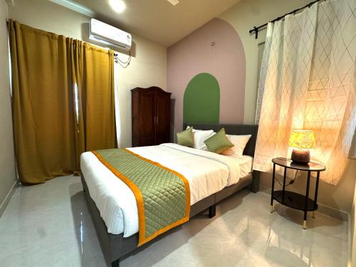 a bedroom with a bed and a lamp on a table at Nandi Daybreak - Holiday Homes in Bengaluru