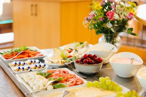 a table topped with different types of food and a vase of flowers at Hotel Rabenstein in Raben Steinfeld