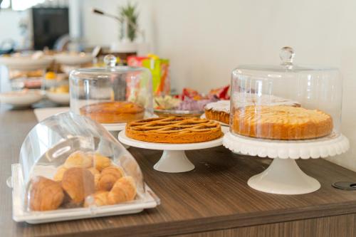 a table topped with trays of pastries and pies at Hotel Ulisse in Marina Romea
