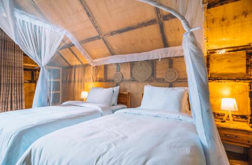 a bedroom with two beds and two lamps at Samora River Lodge in Arusha