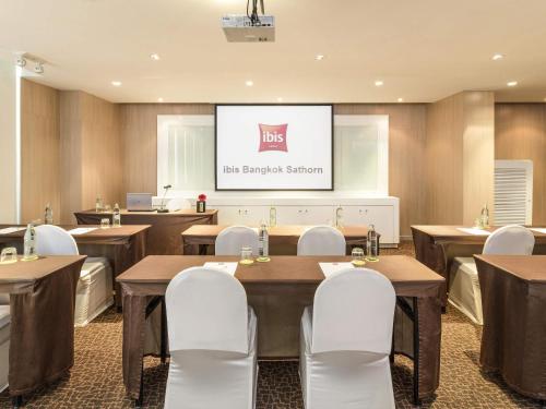 a conference room with tables and chairs and a screen at ibis Bangkok Sathorn in Bangkok