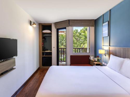 a bedroom with a large white bed and a tv at Ibis Phuket Patong in Patong Beach