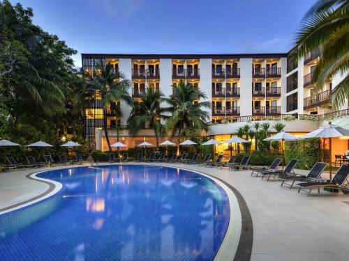 a hotel with a swimming pool in front of a building at Ibis Phuket Patong in Patong Beach