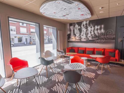 a room with tables and chairs and a red couch at ibis Dunkerque in Dunkerque