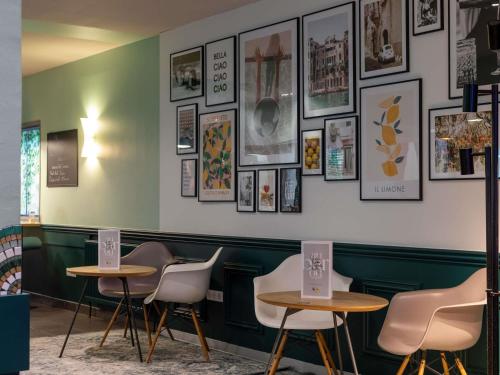 two tables and chairs in a restaurant with pictures on the wall at ibis Dunkerque in Dunkerque