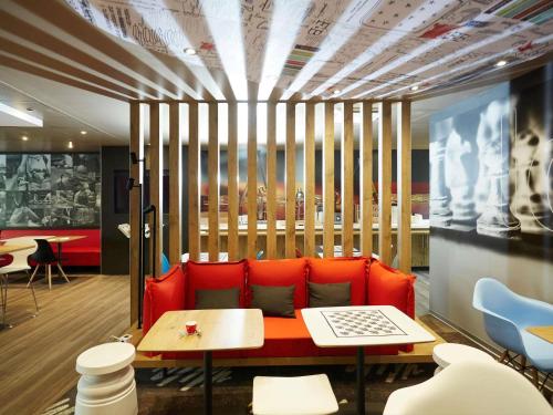 a room with a red couch and a table at ibis Valenciennes in Valenciennes
