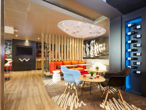 a living room with a couch and a table and chairs at ibis Valenciennes in Valenciennes
