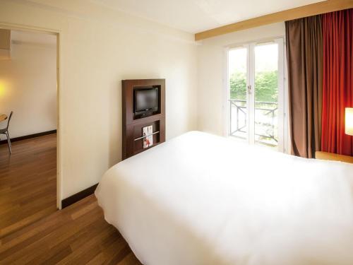 a hotel room with a large bed and a window at ibis Valenciennes in Valenciennes