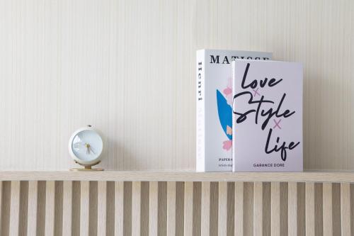 two books sitting on a shelf with a clock at Andaman Sea Best Pool Access and Villas in Phuket Town