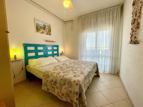 a bedroom with a bed with a blue headboard and a window at Comfy flat for four-Beahost in Porto Santa Margherita di Caorle