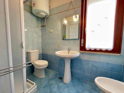 a blue tiled bathroom with a toilet and a sink at Comfy flat for four-Beahost in Porto Santa Margherita di Caorle