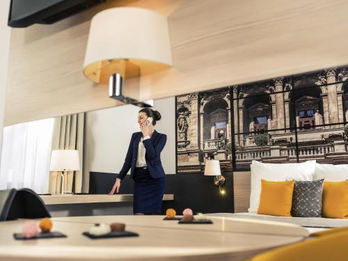 a woman talking on a cell phone in a hotel room at Mercure Budapest City Center in Budapest