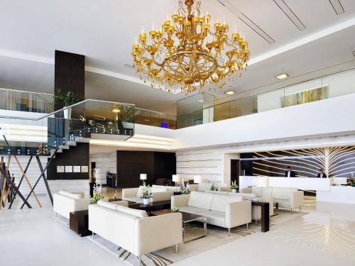 a lobby with white furniture and a chandelier at Novotel Dubai Al Barsha in Dubai