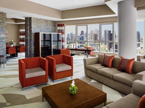 a living room with a couch and chairs and a table at Novotel Dubai Al Barsha in Dubai