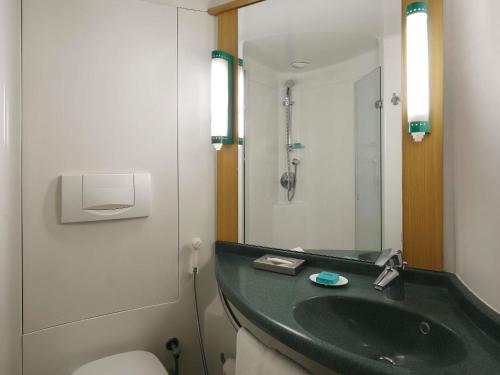 a bathroom with a sink and a toilet and a mirror at ibis Pune Viman Nagar - An Accor Brand in Pune