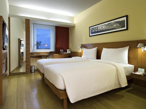 a bedroom with a large white bed and a window at ibis Pune Viman Nagar - An Accor Brand in Pune