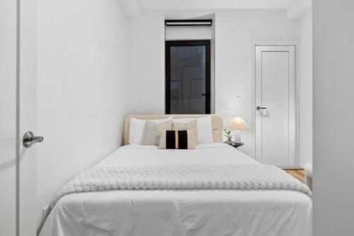 a white bed with white sheets and pillows at Brookline LUX Apt Rooftop GameRoom Subway in Brookline