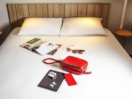 a red purse and other items on a bed at Ibis Pontarlier in Pontarlier
