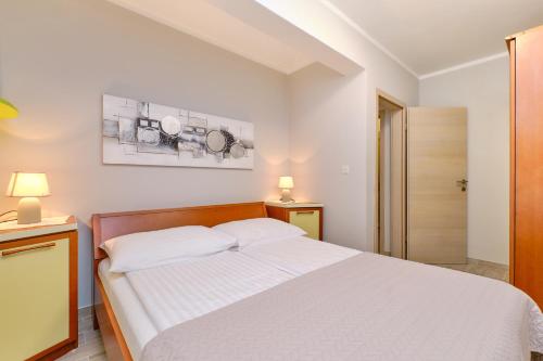 Un dormitorio con una cama blanca y dos lámparas. en Apartmani Enna, en Mali Lošinj