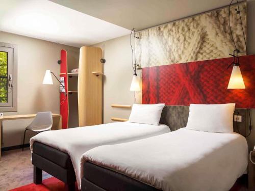 a hotel room with two beds and a red wall at Ibis Budapest Heroes Square in Budapest