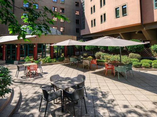 an outdoor patio with tables and chairs and umbrellas at Ibis Budapest Heroes Square in Budapest