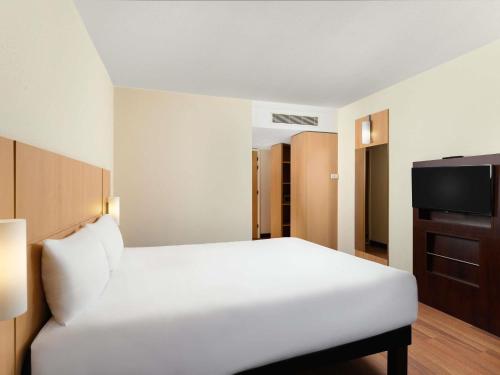 a bedroom with a white bed and a television at Ibis Budapest Heroes Square in Budapest