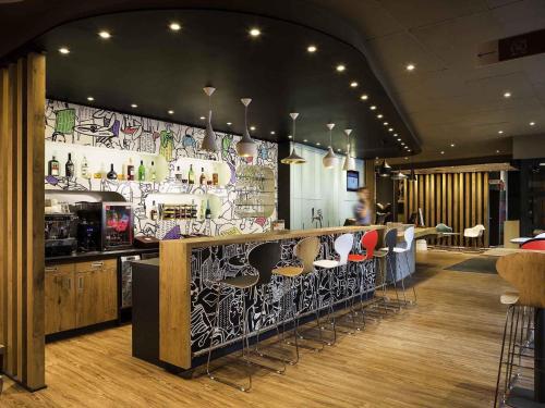 a restaurant with a bar with stools in a room at Ibis Budapest Heroes Square in Budapest
