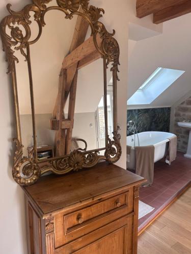 a mirror on top of a wooden dresser with a bath tub at Maisonnette des Sources in Moigny