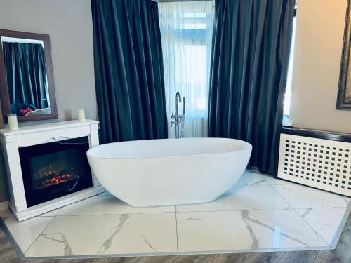 a bathroom with a large white tub in front of a fireplace at Treekos Suite Hotel Istanbul Airport in Arnavutköy