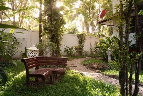 a wooden bench sitting in the grass near a fence at Paradise Island Estate in Choeng Mon Beach