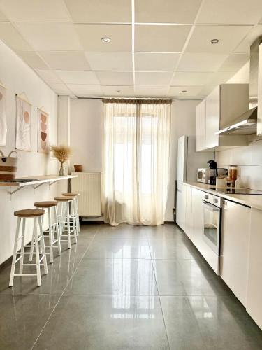a kitchen with white cabinets and bar stools at Spacious duplex in the center of Bastogne Onikos rooms in Bastogne