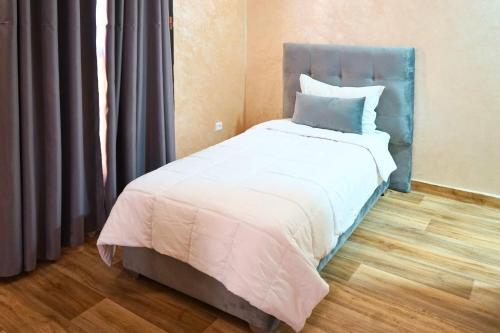 a bed with a blue headboard in a room at Hotel Nouzha in Fès