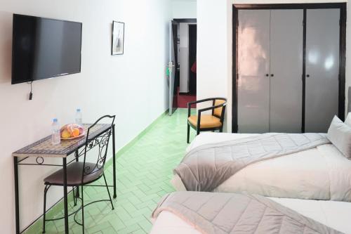 a hotel room with two beds and a table and a tv at Hotel Nouzha in Fès