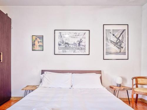 une chambre blanche avec un lit et trois tableaux au mur dans l'établissement Bright Finalborgo Apartment, à Finale Ligure