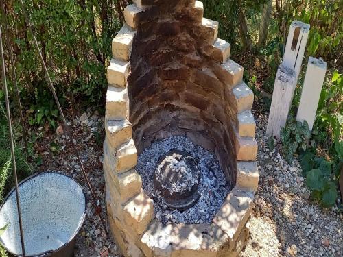 a stone fire pit in a garden with a grill at Holiday Home Paunovaca in Erdut