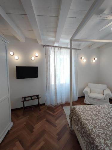 a bedroom with a bed and a tv and a chair at La Via della Giudecca in Siracusa