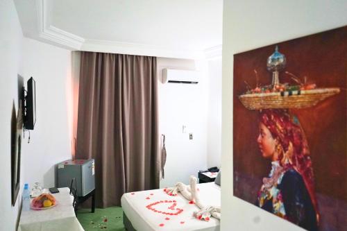 a room with two beds and a painting of a woman at Hotel Nouzha in Fès