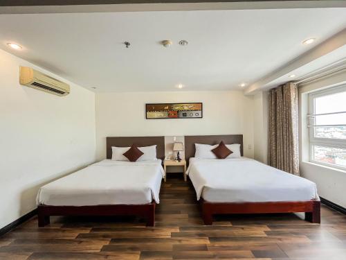 a hotel room with two beds and a window at Quoc Cuong Center Da Nang Hotel by Haviland in Da Nang
